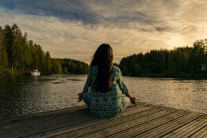 Mujer de espaldas en muelle frente a lago