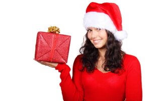 Mujer vestida de rojo con gorro de navidad sosteniendo un regalo