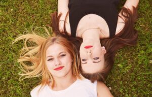 Par de amigas recostadas en el pasto